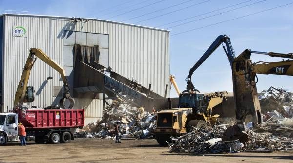 Photo of scrap metal being moved around by cranes at a recycling centre.