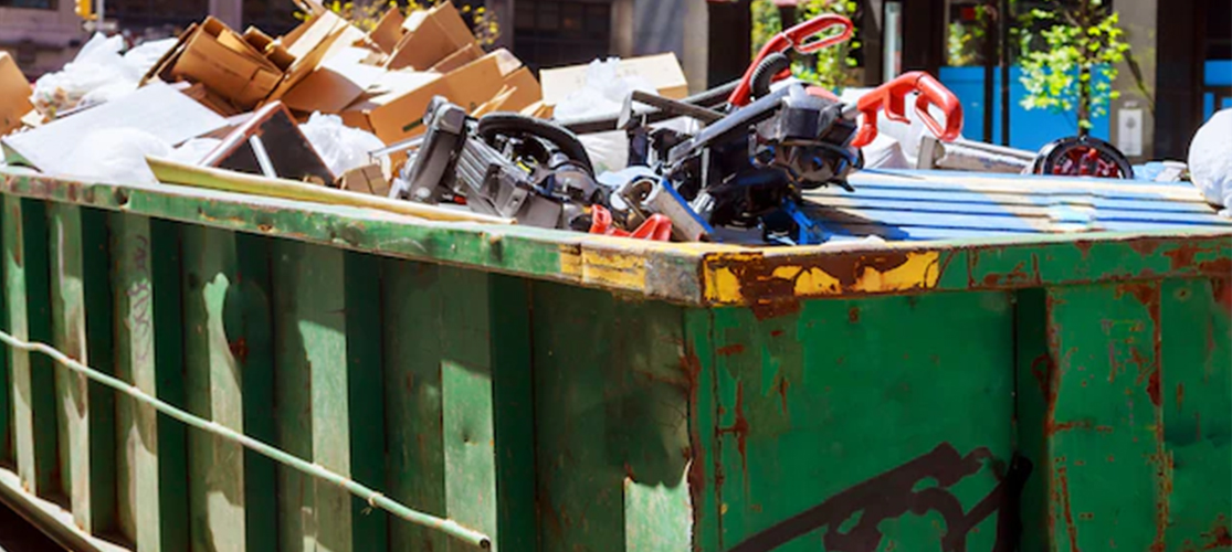 Photo of dark green skip filled with waste.