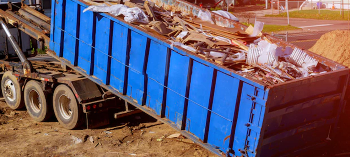 Photo of a lorry unloading a full skip off of the back of it