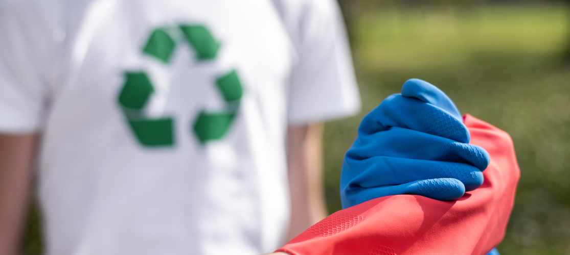 Photo of 2 people wearing gloves shaking hands while another person wearing a white t-shirt with the green recycling logo stands in the background.